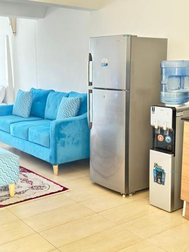 a living room with a blue couch and a refrigerator at Sea la Blue in Ukunda