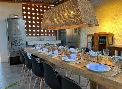 a long wooden table with chairs and a large chandelier at Flô Casa Hotel in Trancoso