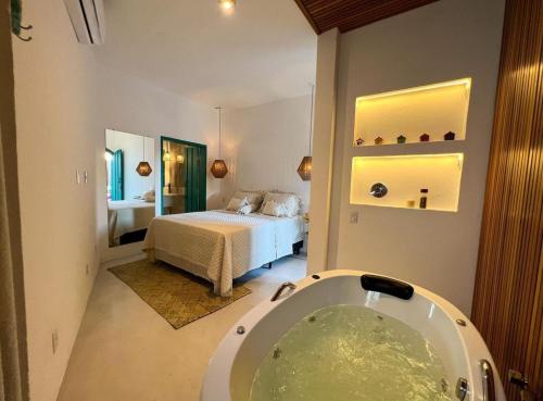a bathroom with a tub and a bedroom with a bed at Flô Casa Hotel in Trancoso