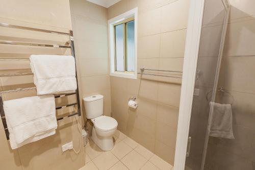 a bathroom with a toilet and a shower with towels at Lazy K - Hideaway in Kalkite