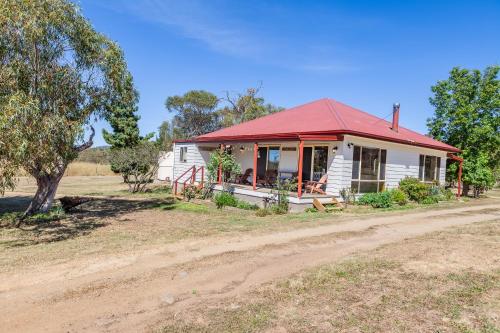 a small white house with a red roof on a dirt road at Lazy K - Hideaway in Kalkite