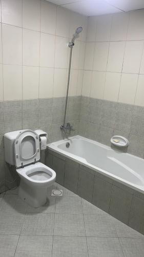 La salle de bains est pourvue de toilettes et d'une baignoire. dans l'établissement F22,R2 Sea&city view room in three bedroom apartment, separate bath outside, à Ajman