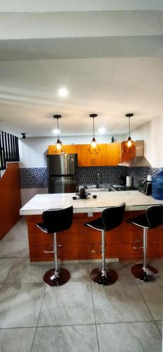 a kitchen with a counter and two bar stools at Suite Puerto de las Islas in Oaxaca City