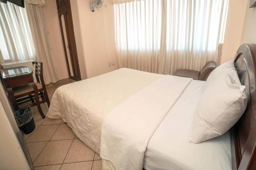 a hotel room with a white bed and a chair at Hotel Torre Norte in Trujillo