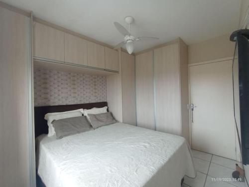 1 dormitorio con 1 cama blanca y ventilador de techo en Apartamento 2 Km da BR101 en São José