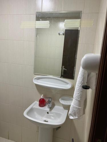 uma casa de banho branca com um lavatório e um espelho em F22,R2 Sea&city view room in three bedroom apartment, separate bath outside em Ajman