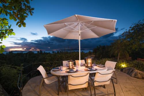 una mesa con sombrilla en el patio en On The Rocks Villa, en Spanish Town