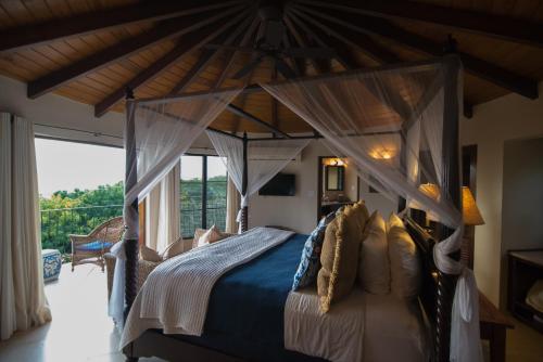 a bedroom with a canopy bed with a large window at On The Rocks Villa in Spanish Town