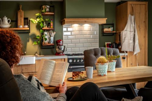 a woman sitting at a table reading a book at Vakwerkloft in Valkenburg