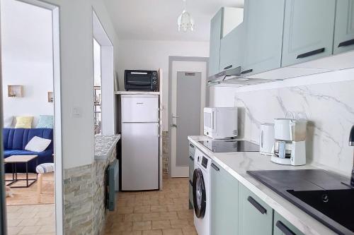une cuisine avec des armoires blanches et une laveuse et une sécheuse dans l'établissement AD18 - L'escale Aultoise chez Hugo, à Ault