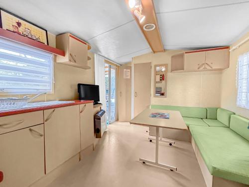 Cette petite chambre comprend un canapé vert et une table. dans l'établissement N34 Nature et Confort à Sarlat-la-Canéda, à Sarlat-la-Canéda