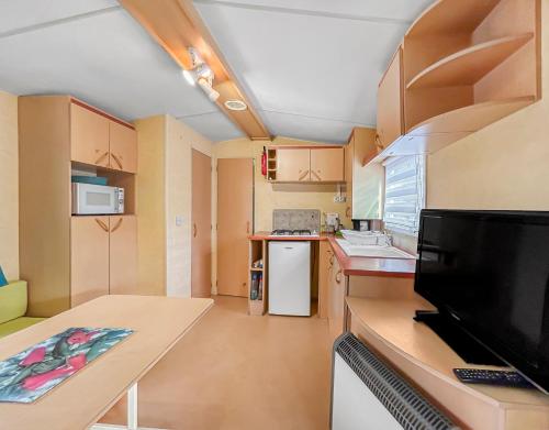 une petite cuisine avec une table et une télévision dans l'établissement N34 Nature et Confort à Sarlat-la-Canéda, à Sarlat-la-Canéda