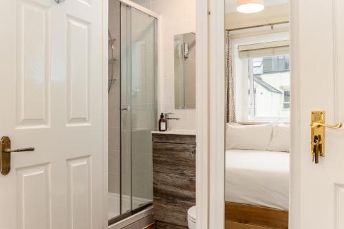a bathroom with a glass shower and a bed at Cragwood Guesthouse in Keswick