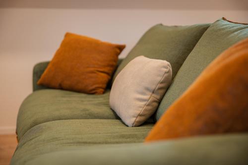 a green couch with three pillows on it at Le 1552 - Gîte de charme - Parking Gratuit in Bergheim