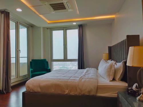 - une chambre avec un grand lit et une chaise verte dans l'établissement One bed appartment in GOLDCrest DHA Lahore, à Lahore