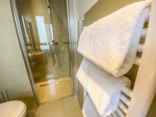 a bathroom with a shower and a pile of towels at Hotel Waldschlößchen in Mülheim an der Ruhr