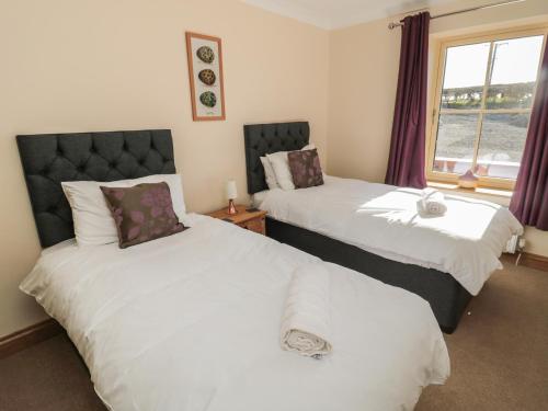 a bedroom with two beds and a window at Glebe Cottage in Alnwick