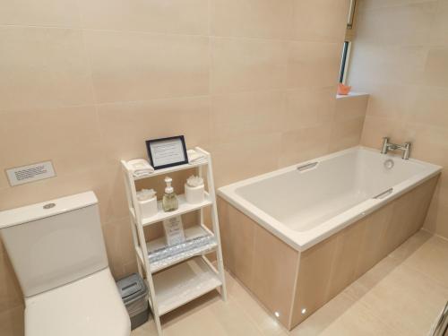 a bathroom with a tub and a toilet and a sink at Glebe Cottage in Alnwick