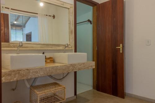 Baño con 2 lavabos y espejo en Pariri Suites, en Trancoso