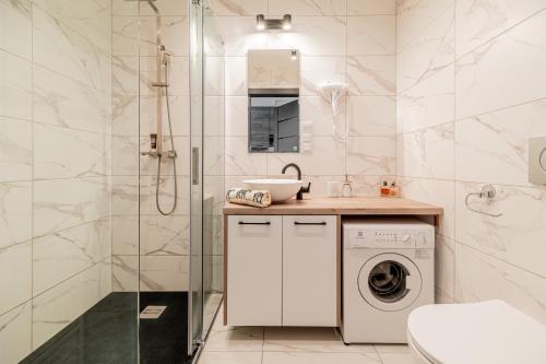 a bathroom with a washing machine and a shower at Aqua Vista apartament Shellter in Rogowo