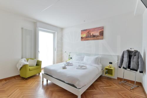 a white bedroom with a bed and a chair at Le Lion Apartments - Bike & Ski in Aosta