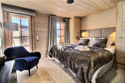 a bedroom with a large bed and a blue chair at Résidence Oscar - Chalet Oscar - 12 Personnes - Les Gets MAE-3871 in Les Gets