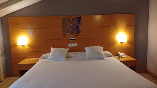 a bedroom with a large white bed with two lamps at Ruta Jacobea in Lavacolla