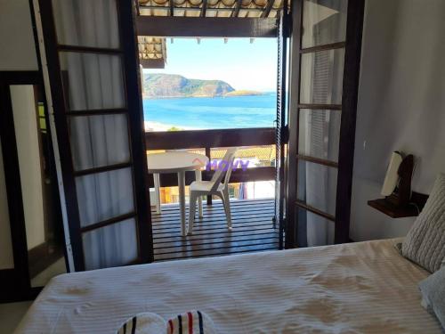 a bedroom with a bed and a view of the ocean at CAMBOINHAS BnB in Niterói