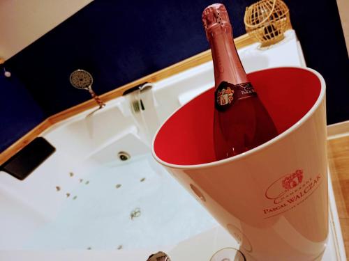 Una botella de champán en un cubo junto a una bañera. en Studio cosy, grand spa privatif et parking privée Centre ville menton, en Menton