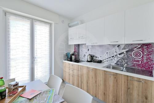 a kitchen with white cabinets and a table with chairs at Le Lion Apartments - Lys Family Apartment in Aosta