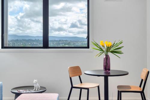 a table and chairs with a vase of flowers on it at Roomie Apartment Hotel in Auckland