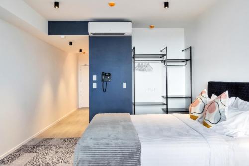 a bedroom with a bed and a blue wall at Roomie Apartment Hotel in Auckland