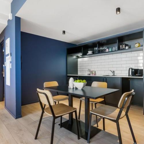 a dining room with a black table and chairs at Roomie Apartment Hotel in Auckland