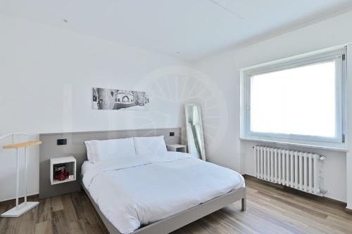 a white bedroom with a bed and a window at Le Lion Apartments - Bike & Ski in Aosta