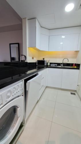 a kitchen with white cabinets and a dishwasher at Beachfront Home with Sea View - 2BR, 134m2 in Lusail