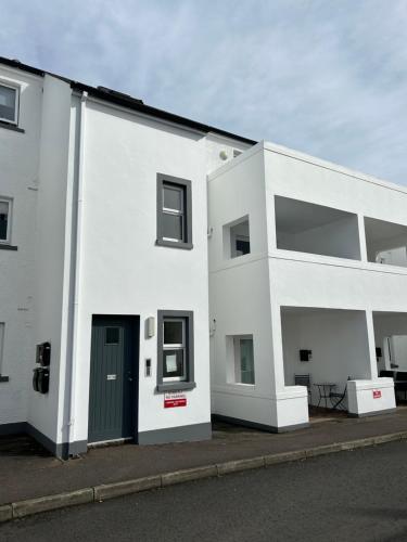 a white building with a green door on a street at Seaside Marine First Floor Apartment in Ballycastle