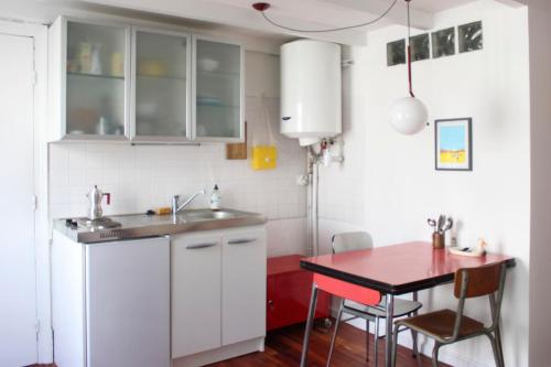 une cuisine avec des placards blancs et une table rouge dans l'établissement Cosy studio in Paris, à Paris