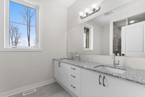 a white bathroom with a sink and a window at Muskoka Retreat Stunning Hilltop Views in Huntsville