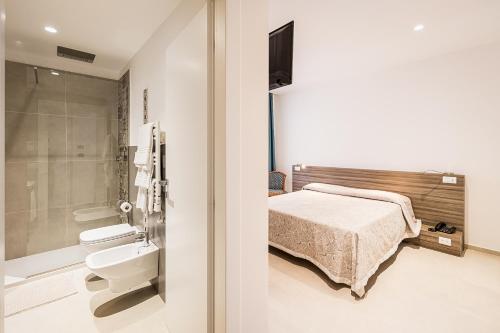 una camera con letto e un bagno con servizi igienici di Hotel Nuova Grottella a Copertino