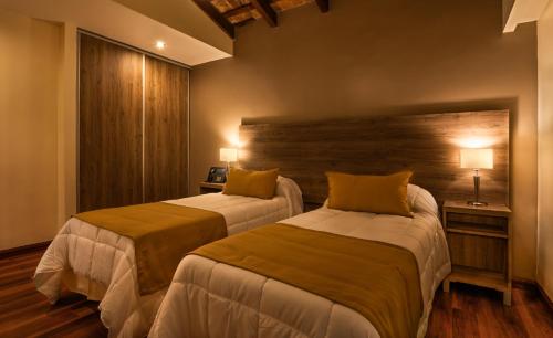 a bedroom with two beds and a wooden wall at Hotel Intersur La Cumbre in La Cumbre