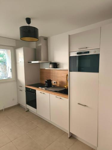  La cuisine est équipée de placards blancs et d'un réfrigérateur. dans l'établissement Neuf, calme, 10 minutes du centre de Paris, à Saint-Denis