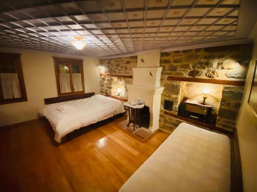 Aristotelous Alexandrou Historic Inn في أرنايا: غرفة نوم مع سرير ومدفأة حجرية