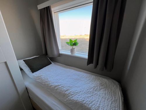 a small bedroom with a bed and a window at Garður Apartments in Gardur