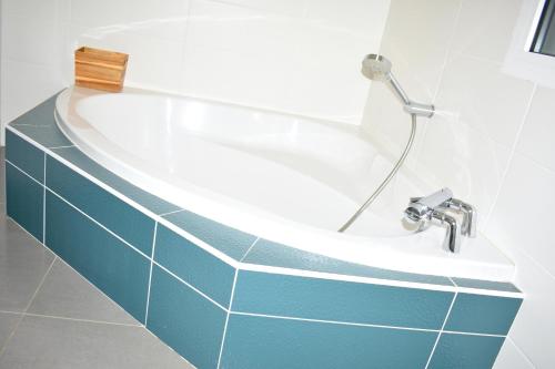 uma banheira na casa de banho com azulejos azuis em Villa neuve sur pilotis vue mer à 30m de la plage em Plérin