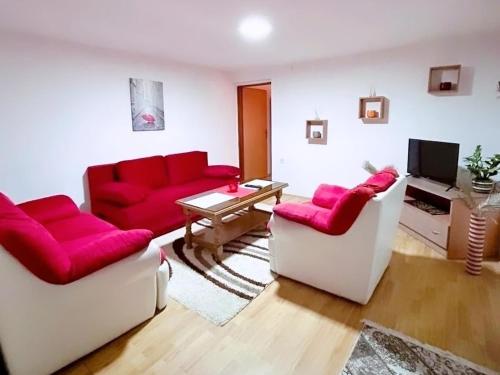 een woonkamer met twee rode banken en een televisie bij Apartman 053 in Doboj