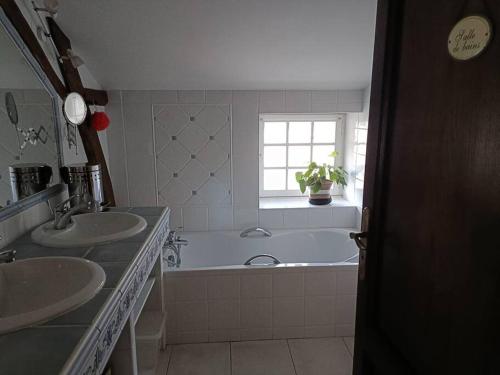 baño con 2 lavabos y bañera con ventana en Le Moulin de Malfiance proche Futuroscope en Doussay