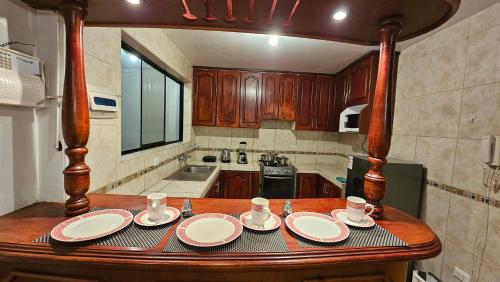 a kitchen with a wooden table with plates and cups at Los Profesionales Hospedaje in Cusco
