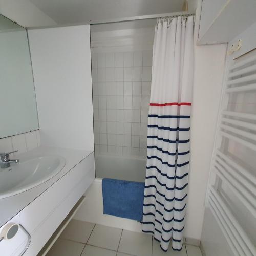 une salle de bain avec un lavabo et un rideau de douche dans l'établissement Appartement à Port Bourgenay, vue sur lac, au pied d'un parc aquatique, à Talmont-Saint-Hilaire