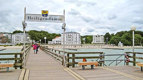 a wooden pier with benches and a sign on it at Pension Ostsee-Strand in Börgerende-Rethwisch