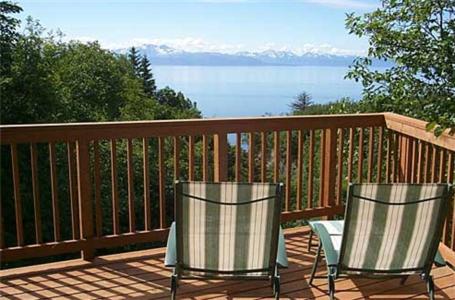 two chairs on a deck with a view of the water at Alaska Adventure Cabins in Homer